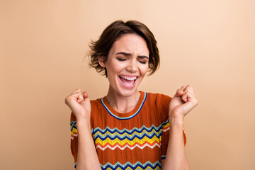 Canvas Print - Photo of pretty delighted person closed eyes raise fists achieve shout yes hooray isolated on beige color background