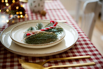 Wall Mural - beautiful christmas table setting, decor with green fir tree branch and candy cane on plates, cutler