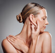 © KayExam/peopleimages.com - Beauty, hand and profile of mature woman in studio on gray background for facial cosmetics. Face, skincare and touching with confident person at salon or spa for antiaging dermatology treatment