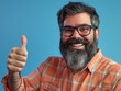 © Tanakrit - A smiling man with glasses gives a thumbs-up against a blue background, showcasing a friendly and approachable demeanor.