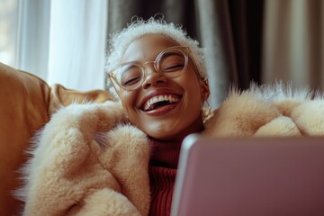 A woman is smiling while using a laptop, perfect for illustrations about work from home or technology