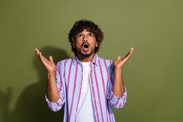 Sticker - Photo of arab businessman in striped casual shirt and eyeglass raised hands up looking at falling rain isolated on khaki color background