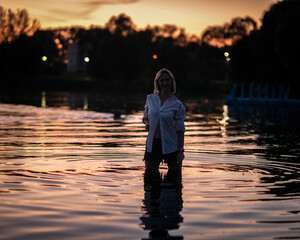 Portrait of a young beautiful blonde girl on the river on a summer evening.