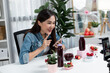 © Summit Art Creations - Smiling young beautiful Asian reviewing tasty mixed strawberry and cherry juice detox drinks, showing healthy product to promote for special promotion selling on social media online record. Stratagem.