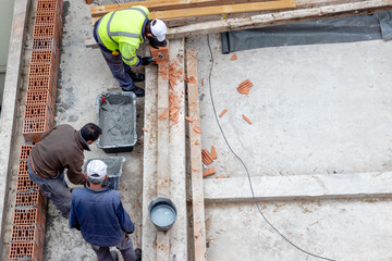 Construction workers prepare cement and mortar for building brick walls. Masons builds a house from building blocks and plaster.