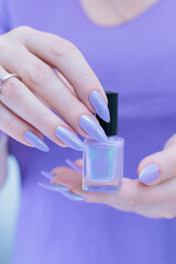 Wall Mural - Female hand with long nails and a lilac blue nail polish