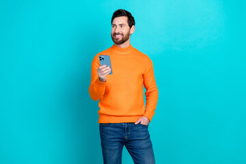Poster - Photo of attractive positive joyful young man wear trendy clothes use phone empty space isolated on cyan color background