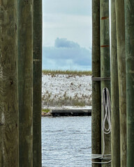 A view of the beach shore that is framed by wooden poles on a dock