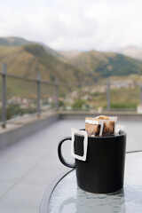 Drip coffee bag with ground coffee in cup. Making freshly coffee in mug. freshly brewed black coffee. Preparation of freshly brewed hot drink in nature.