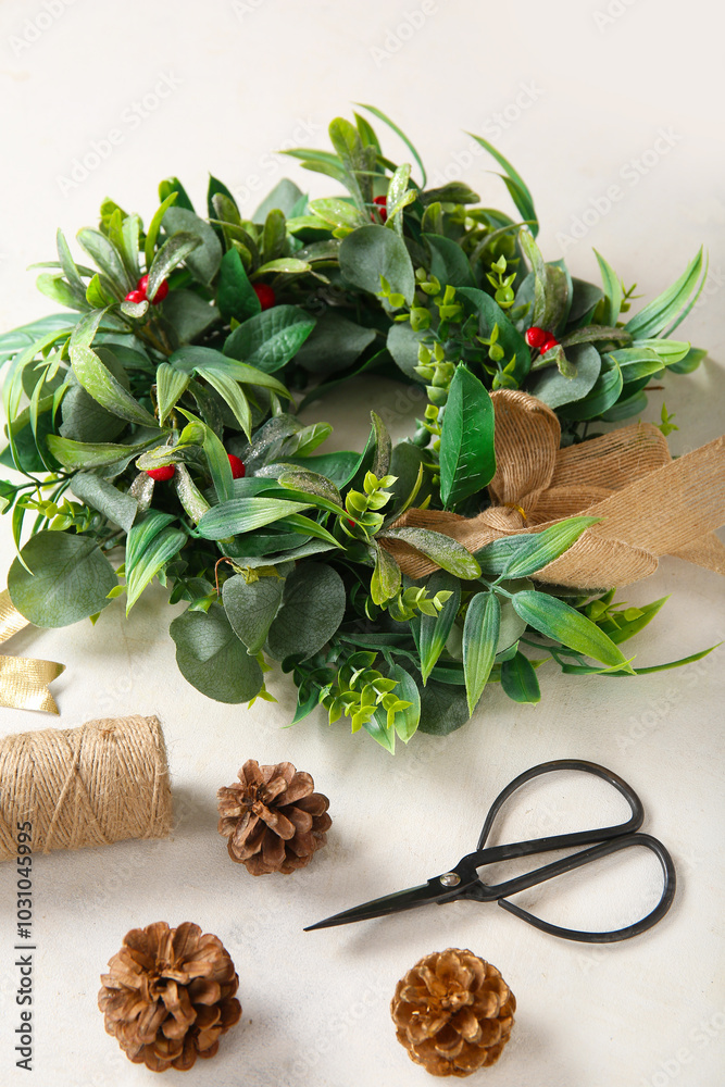Beautiful mistletoe wreath, scissors, pine cones and rope on white background