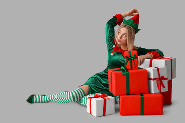 Poster - Young woman in elf costume with Christmas gift boxes on white background