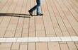 © Anette - Blaue Jeanshosenbeine und braune Schuhe von über Platz gehender Mann mit Schattenreflexion in Stadt bei Sonne am Nachmittag im Herbst