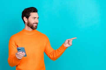 Poster - Photo of attractive blogger man wear trendy clothes hold phone look empty space isolated on cyan color background