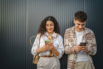 Young couple use mobile phone for explore internet front black wall