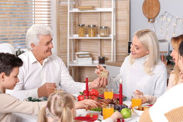 Wall Mural - Mature man giving Christmas gift to his wife while having dinner at table in kitchen