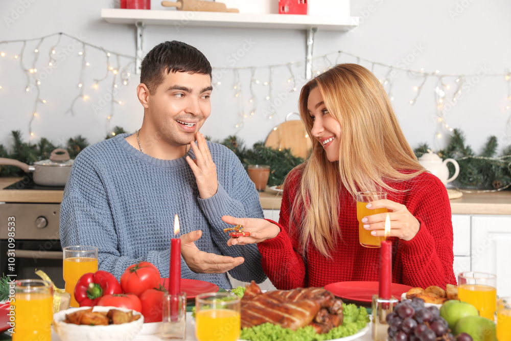 Young couple having Christmas dinner at table in kitchen