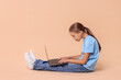 © New Africa - Girl with incorrect posture and laptop sitting on beige background