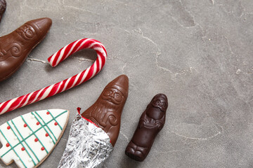 Wall Mural - Chocolate Santa Clauses, cookie and candy cane on grunge background, closeup