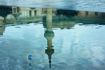 Poster - Reflection of historic architecture in shallow water showcasing the intricate details of minarets and domes during a calm early morning