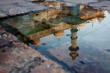 Poster - Reflection of historic architecture in shallow water showcasing the intricate details of minarets and domes during a calm early morning