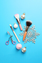 Sticker - Makeup brushes, eyelash curler and Christmas decor on light blue background, flat lay