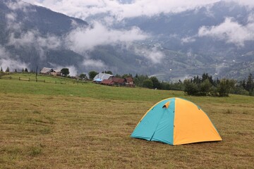 Poster - Camping tent on grass in mountains, space for text