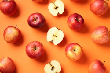 Canvas Print - Whole and cut fresh red apples on orange background, flat lay