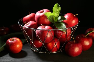 Poster - Fresh ripe red apples and green leaves on black wooden table