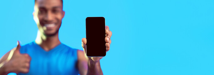 Aufkleber - Workout Application Concept. Unrecognizable Black Sportsman Showing Blank Smartphone Screen Gesturing Thumbs-Up Posing In Studio Over Blue Background. Mockup, Panorama