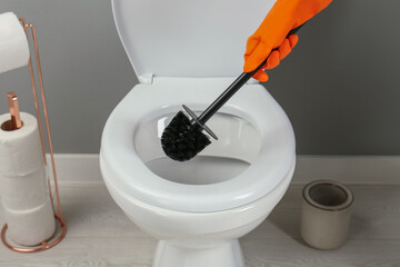 Wall Mural - Woman cleaning toilet with brush in bathroom, closeup