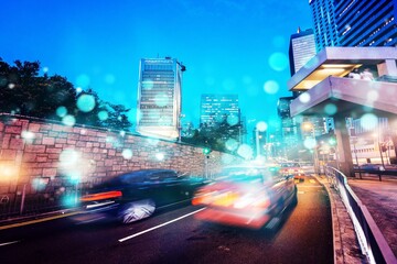 Wall Mural - Night view of Hong Kong city with cars driving on a street lined with skyscrapers.