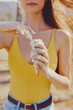 © SHOTPRIME STUDIO - Woman enjoying ice cream in a sunny outdoor setting, with melting ice cream on her hands Bright yellow swimsuit contrasts with natural background