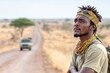 © feeling lucky - A contemplative man gazes into the distance on a rural road, surrounded by savannah landscapes and a distant vehicle.