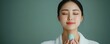 © Intelligent Horizons - Closeup of young Asian woman gently massaging her face with a jade roller in the comfort of her own bedroom as part of her regular beauty routine and natural skincare regimen
