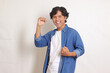 © Yazid Nasuha - Portrait of attractive Asian man in blue shirt raising his fist, celebrating success. Isolated image on white background