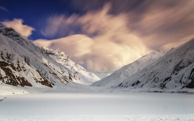 Beautiful scenery in the snow-covered mountain peaks with trees, rocks, and an overcast sky in northern Pakistan.