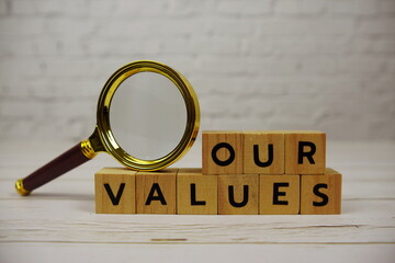 Our Values with wooden blocks alphabet letters and magnifying glass on wooden background