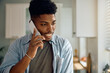© Drazen - Young black man making phone call at home.