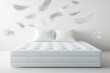 © kristina - White feathers soar above a white mattress, creating a dreamy atmosphere.