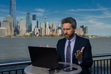 Business man using laptop outdoor in New York City. Business American success. American business dream. American businessmen in suits with laptop near Manhattan. Online business in USA.