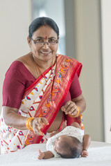 ndian family spending time together, wearing traditional and casual outfits with a baby, a young girl, and grandparents in a high-rise apartment in Kuala Lumpur, Malaysia.