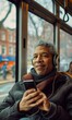 © Natalia - A man wearing headphones looks at his phone while riding public transportation. AI.