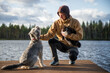 © Cavan Images - Man with dog and cat sitting on a wooden dock