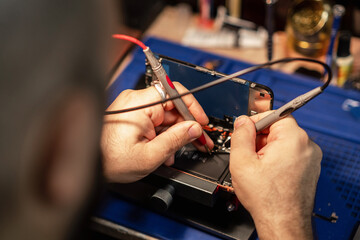 Poster - Technician performing smartphone battery repair in a workshop using precision tools and equipment during the day
