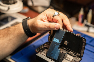 Poster - Expert technician performing smartphone battery repair in a workshop during daytime