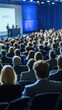 © cosmosgod - Abstract Gathering of a Large Audience at a Conference Stage with a Speaker Against a Blurred Blue Background, Capturing the Atmosphere of Engagement and Collaboration, Ideal for Advertising and Mark