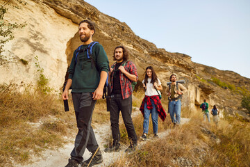 group of young people with backpacks having an excursion about a natural rocky area, enjoying the be