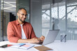© Liubomir - Man smiling while working on laptop in modern office setting. Casual attire with glasses adds to positive work attitude. Shows productivity, business success, technology, and professional lifestyle.