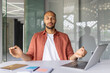 © Liubomir - Man practicing meditation in office setting, sitting at desk with closed eyes. Laptop and notebooks indicate work environment. Promotes mindfulness, stress relief, and focus during work.