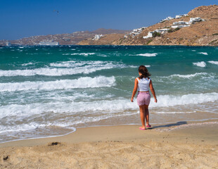 A girl stands on the seashore in a storm on the island of Mykonos in Greece